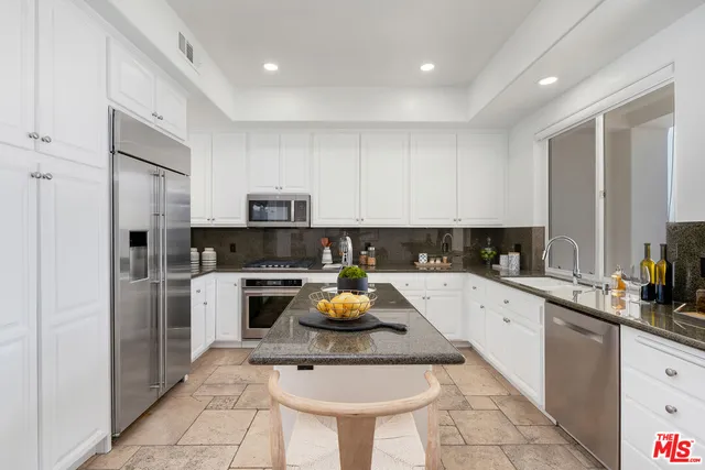 a kitchen with granite countertop a sink and white cabinets