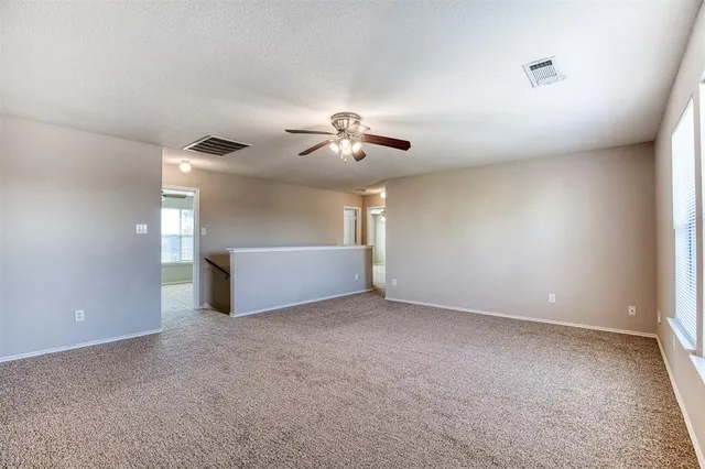 a view of an empty room with a ceiling fan and window