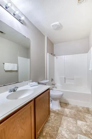 a bathroom with a granite countertop sink toilet a large mirror and bathtub