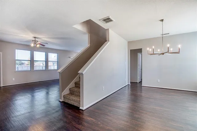 a view of empty room with wooden floor fan and window
