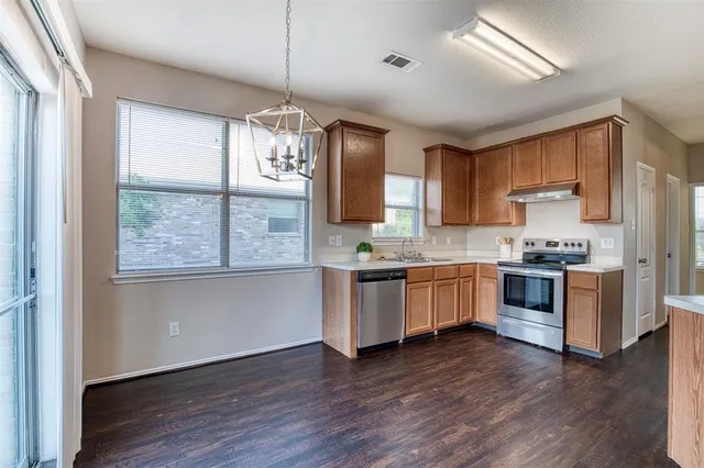 a kitchen with stainless steel appliances granite countertop wooden floors a stove a sink and a window