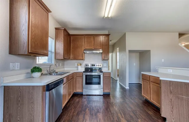 a kitchen with stainless steel appliances granite countertop wooden cabinets a stove top oven a sink and dishwasher