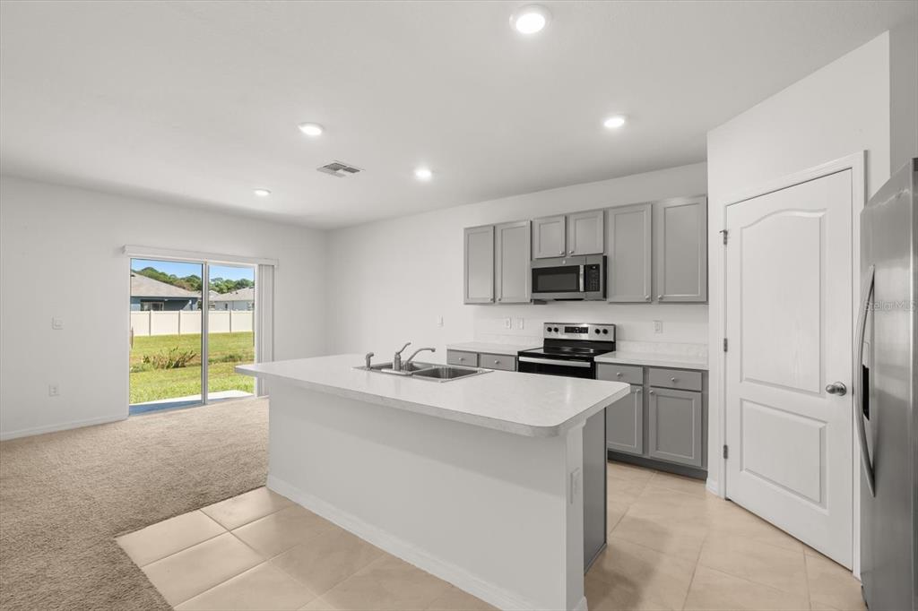 307 Sunset View Drive Edgewater, FL 32141 - Photo 12 of 44 a kitchen with a refrigerator a stove top oven a sink and dishwasher with wooden floor