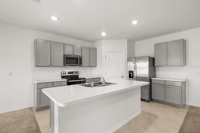 a view of kitchen with refrigerator and white cabinets