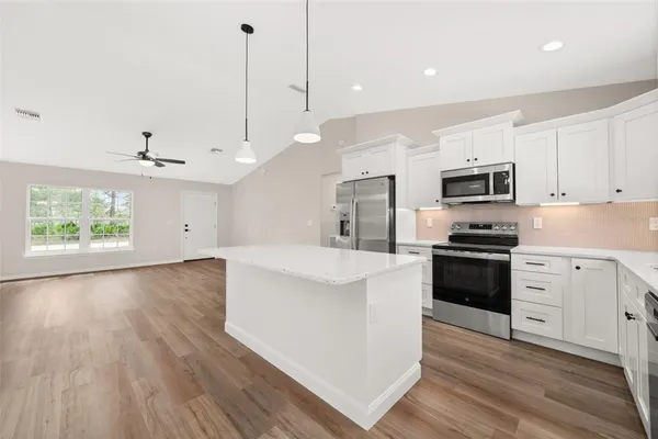 a kitchen with granite countertop a stove a sink and a refrigerator