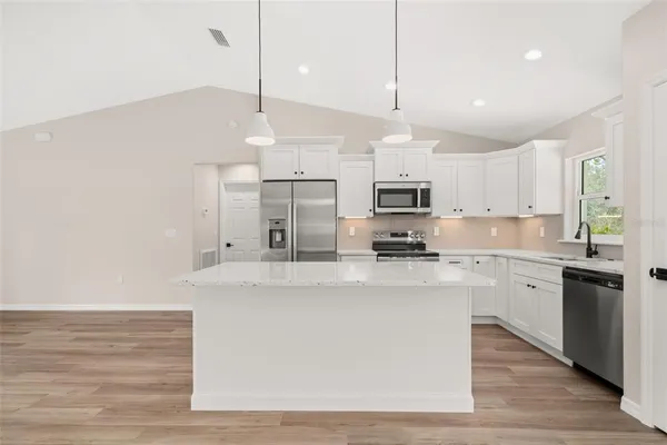 a kitchen with stainless steel appliances granite countertop a sink a stove and a refrigerator