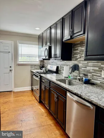 a kitchen with stainless steel appliances granite countertop a sink stove and cabinets