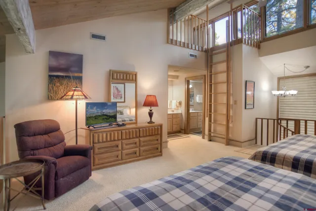 a bedroom with two beds lamp and paintings on the wall