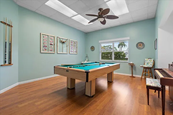 a room with wooden floor pool table and windows