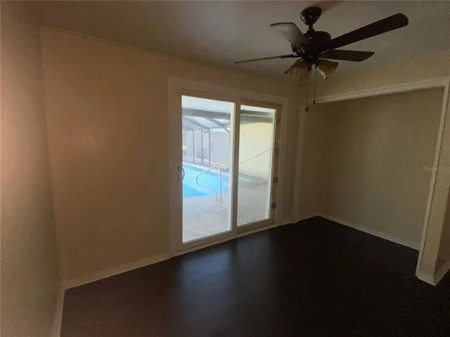 an empty room with wooden floor fan and windows