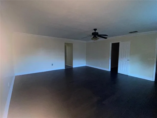 an empty room with wooden floor and ceiling fan