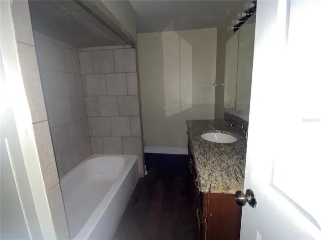 a bathroom with a granite countertop sink a toilet and bathtub