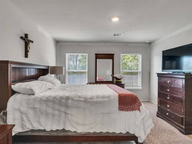 a bedroom with a large bed and a flat tv screen on dresser