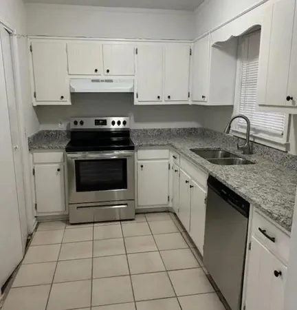 a kitchen with granite countertop a stove sink and cabinets