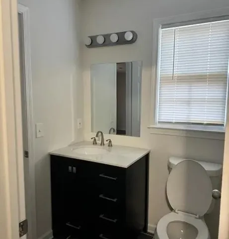 a bathroom with a toilet sink vanity and mirror