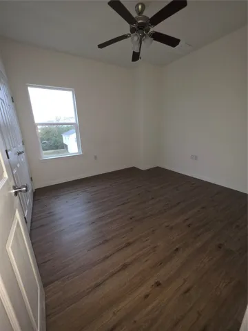 an empty room with wooden floor cabinet and windows