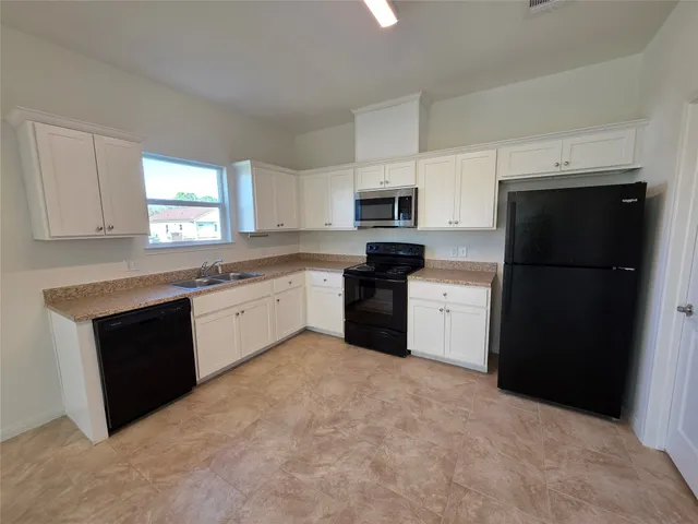 a kitchen with a sink a stove a refrigerator a microwave and cabinets