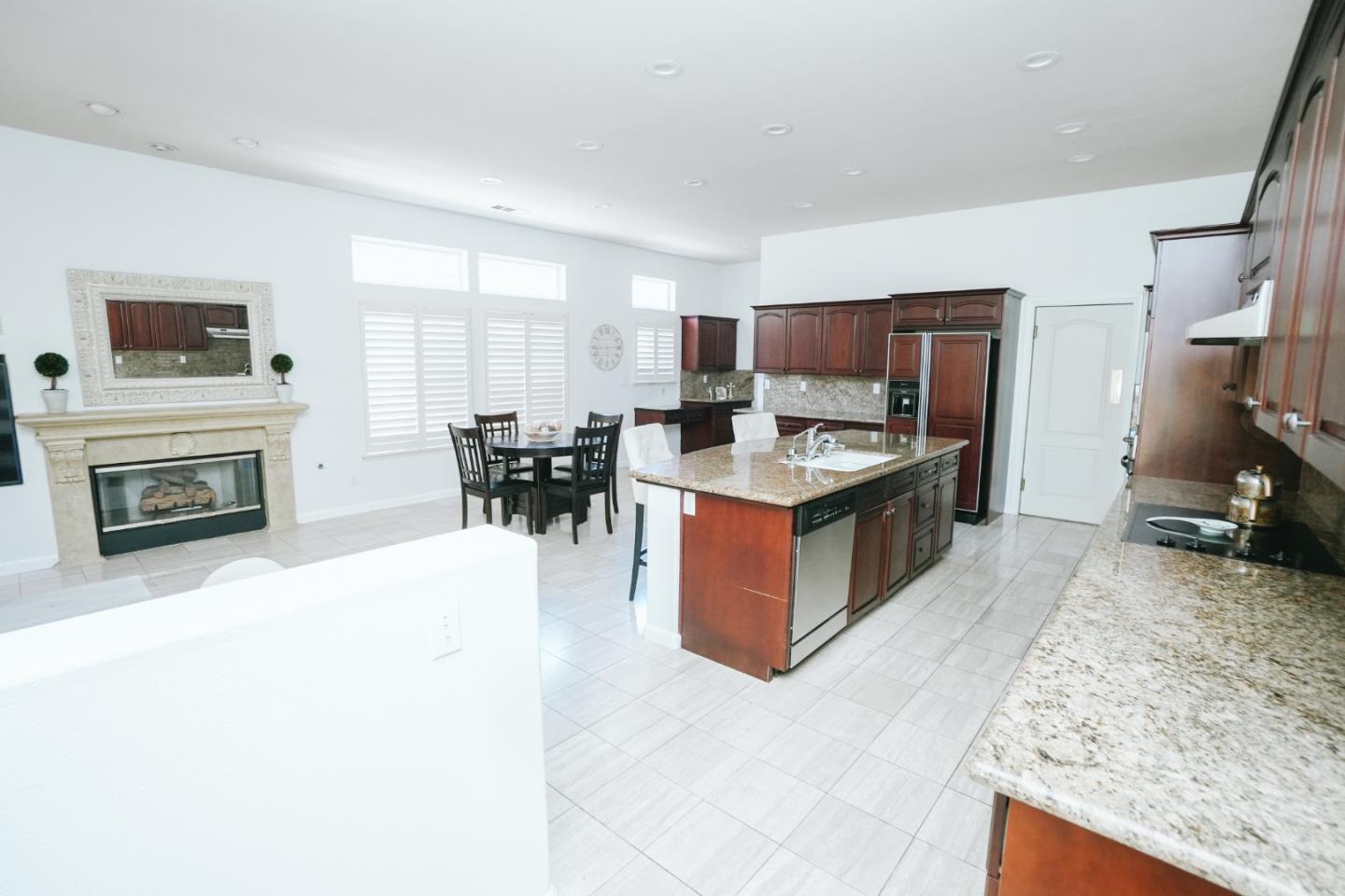 4609 Vía Fiori Modesto, CA 95357 - Photo 25 of 44 a kitchen with stainless steel appliances granite countertop a stove top oven a sink a dining table and chairs