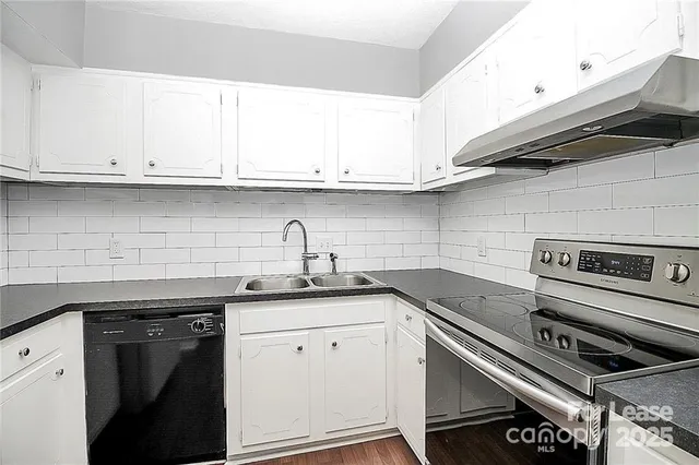 a kitchen with granite countertop a sink stainless steel appliances and white cabinets