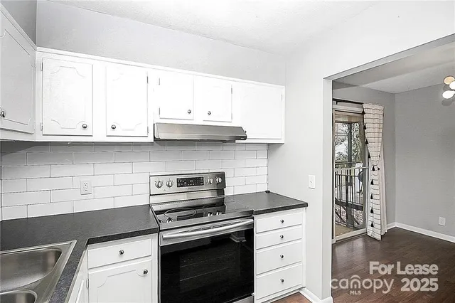 a kitchen with stainless steel appliances granite countertop a stove and a white cabinets