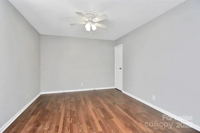 a view of a room with wooden floor and a ceiling fan