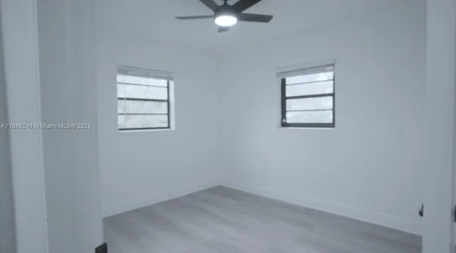 an empty room with windows and ceiling fan