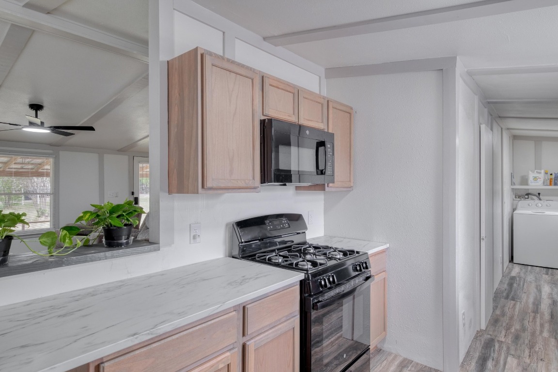 209 Fallwell Street Liberty Hill, TX 78642 - Photo 11 of 25 a kitchen with stainless steel appliances a stove a microwave and a hard wood floor