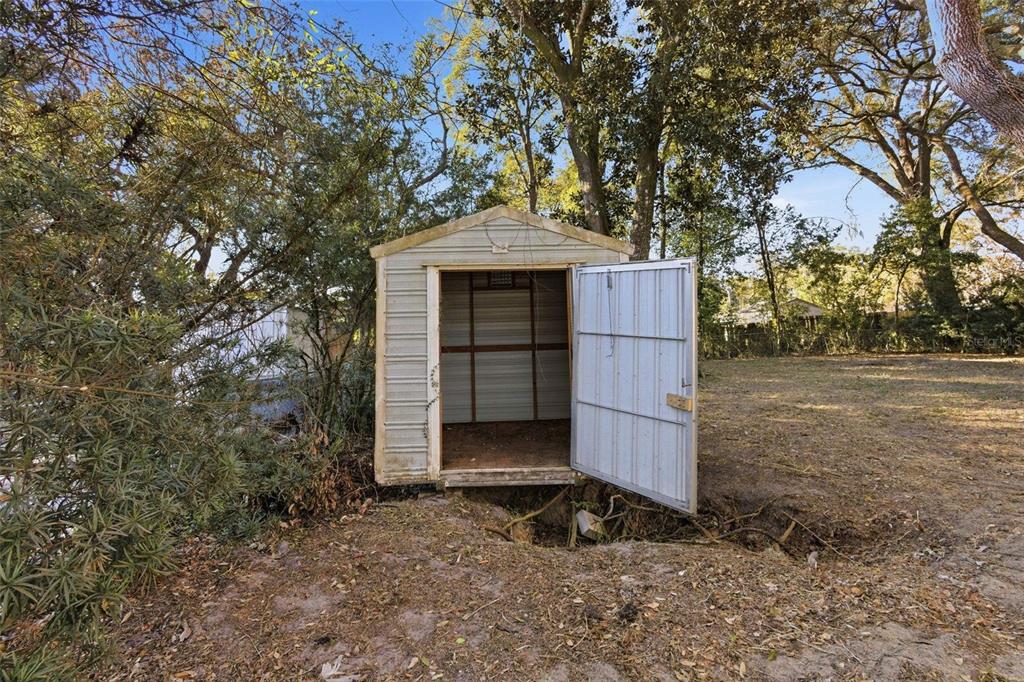 762 Valencia Avenue Orange City, FL 32763 - Photo 24 of 39 a small barn in front of a yard with wooden fence and a large tree