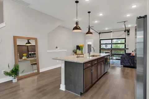 a kitchen with stainless steel appliances granite countertop a sink a counter space and wooden floor