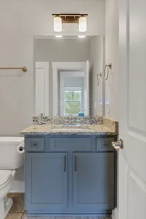 a bathroom with a granite countertop toilet a sink and a mirror