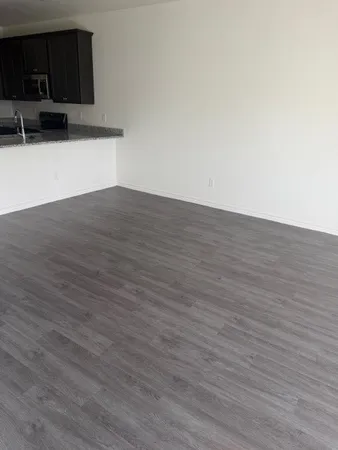 a view of an empty room with wooden floor and a cabinet