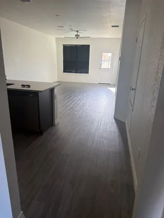 an empty room with wooden floor and a kitchen