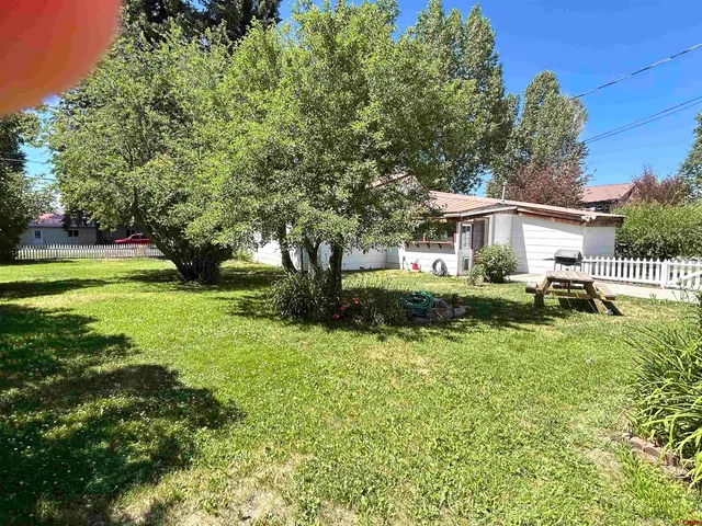 a view of a house with a big yard plants and large trees