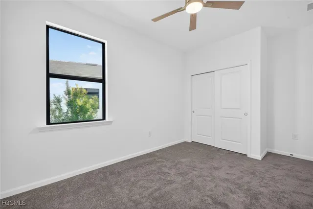 an empty room with a window and a ceiling fan