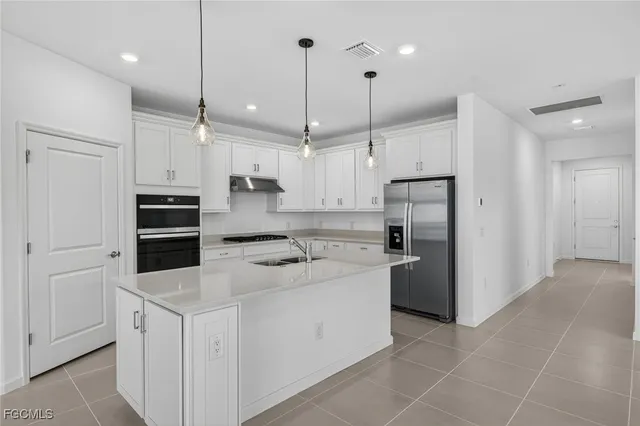 a kitchen with stainless steel appliances a stove a sink a refrigerator a center island with wooden floor