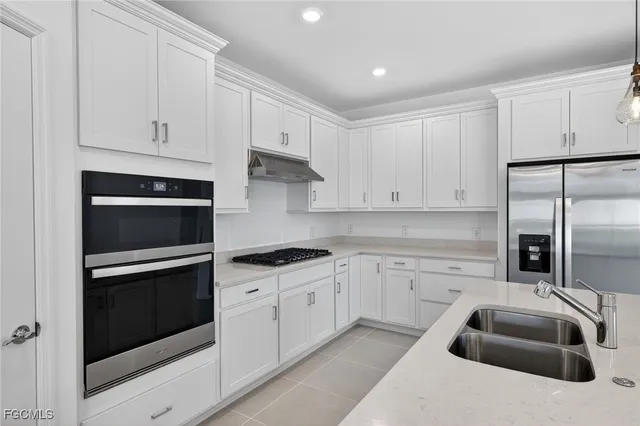 a kitchen with granite countertop white cabinets and stainless steel appliances