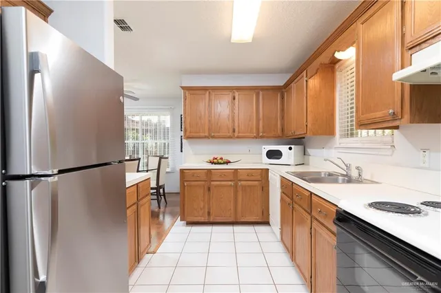 a kitchen with a sink a refrigerator and a stove top oven