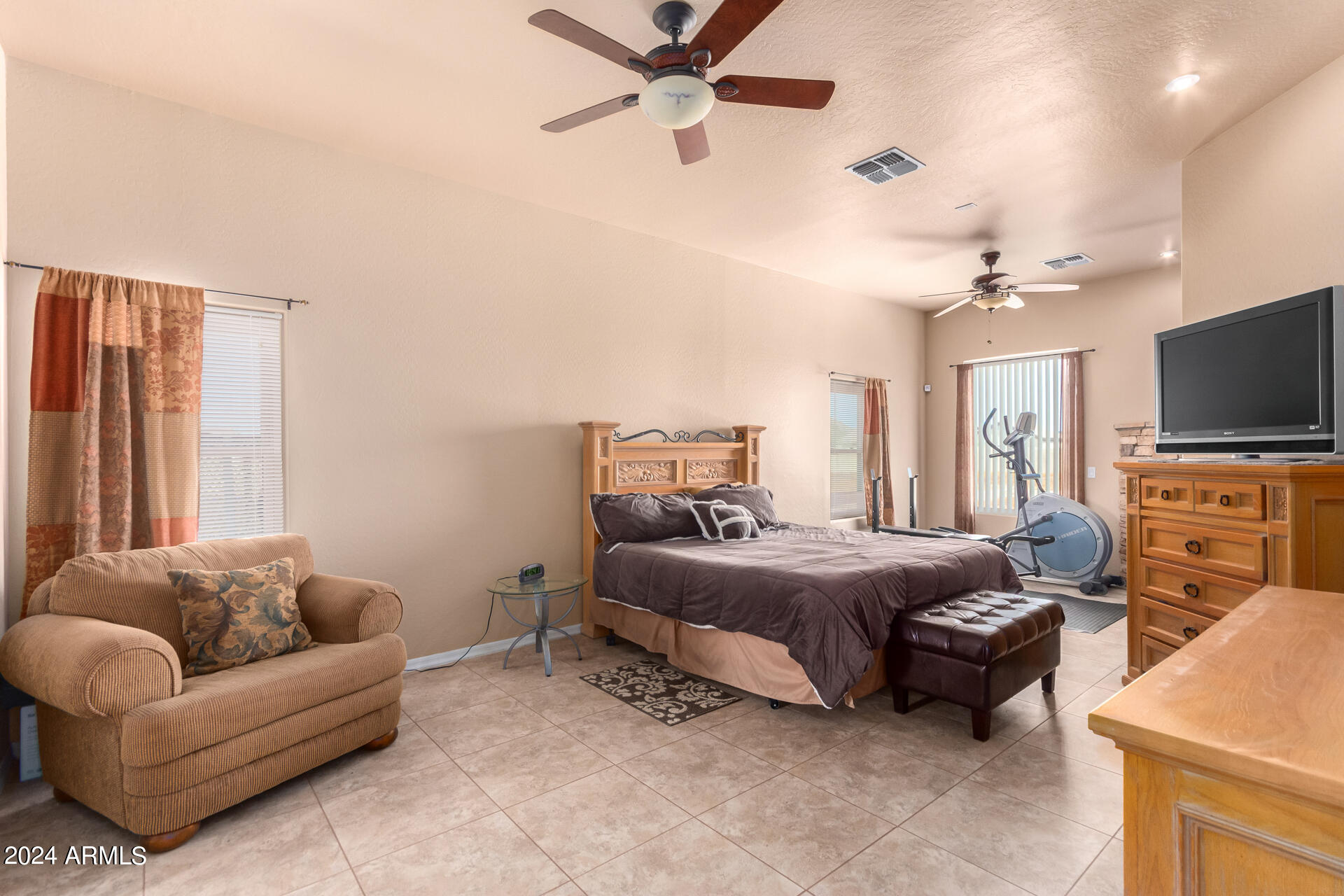 6786 Gelding Lane Coolidge, AZ 85128 - Photo 23 of 39 a spacious bedroom with a bed a couch and a flat screen tv