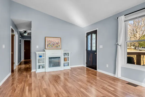a view of an empty room with a window and wooden floor