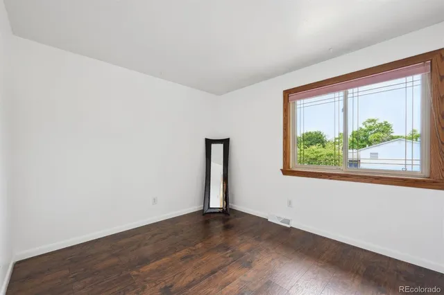 an empty room with wooden floor and a window