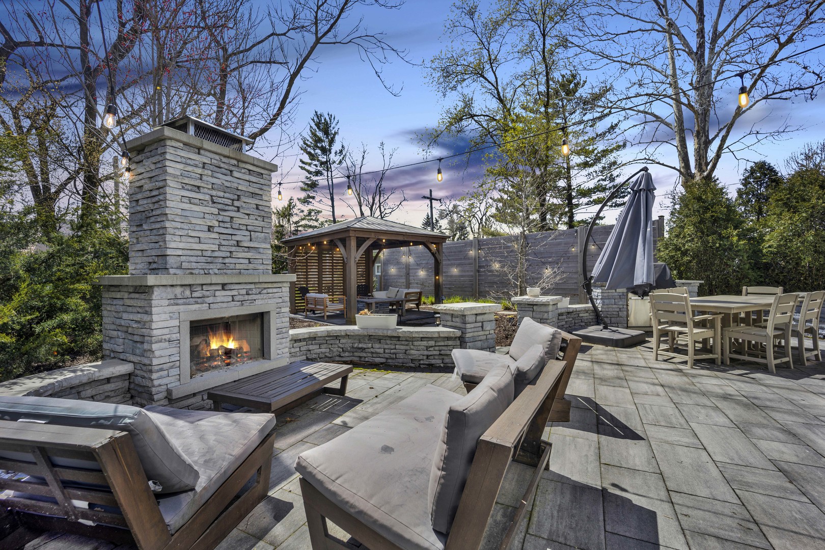 317 Lionel Road Riverside, IL 60546 - Photo 34 of 47 a view of a patio with table and chairs with a fire pit and large trees