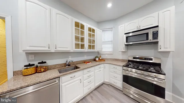 a kitchen with stainless steel appliances white cabinets and a stove top oven