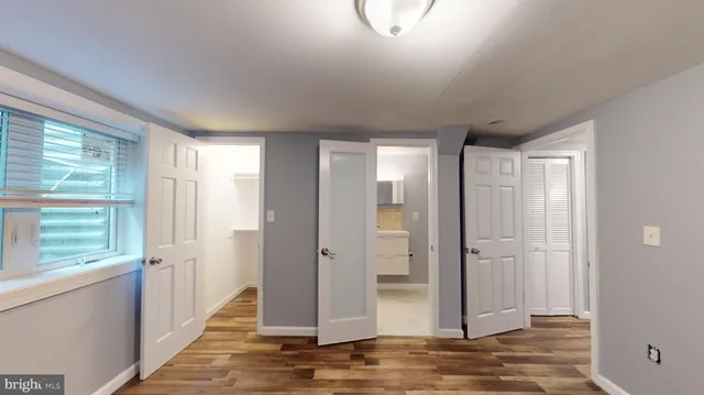 a view of a hallway with wooden floor and a bathroom