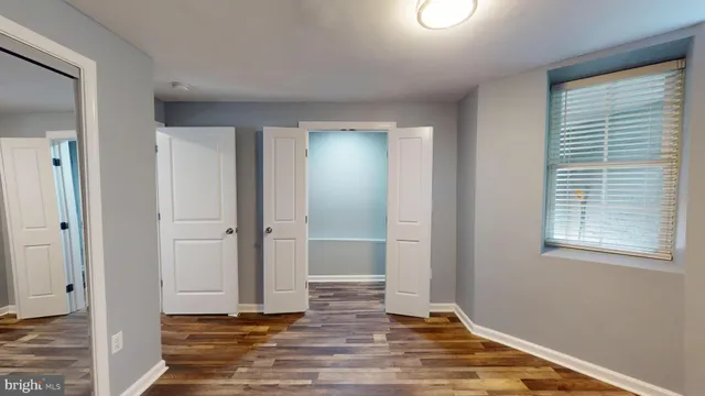 a view of an empty room with wooden floor and a window