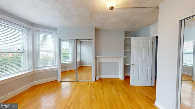 a view of empty room with wooden floor and seating space