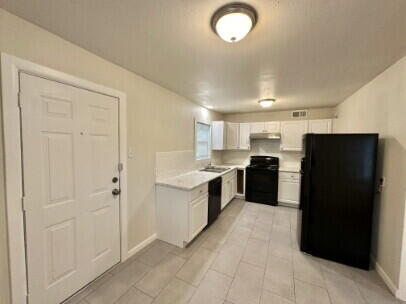 4214 37th Street Lubbock, TX 79413 - Photo 5 of 14 a large kitchen with a refrigerator and white cabinets