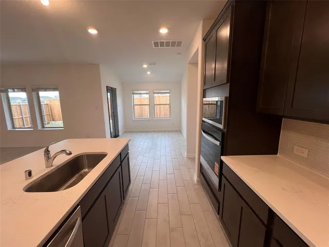 a kitchen with granite countertop stainless steel appliances sink stove top oven and refrigerator