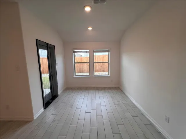 an empty room with wooden floor and windows