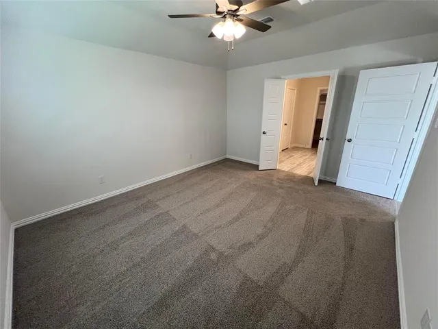 an empty room with a ceiling fan and a window