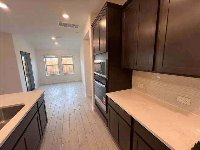 a kitchen with stainless steel appliances granite countertop a refrigerator a sink dishwasher a stove and white countertops with wooden floor